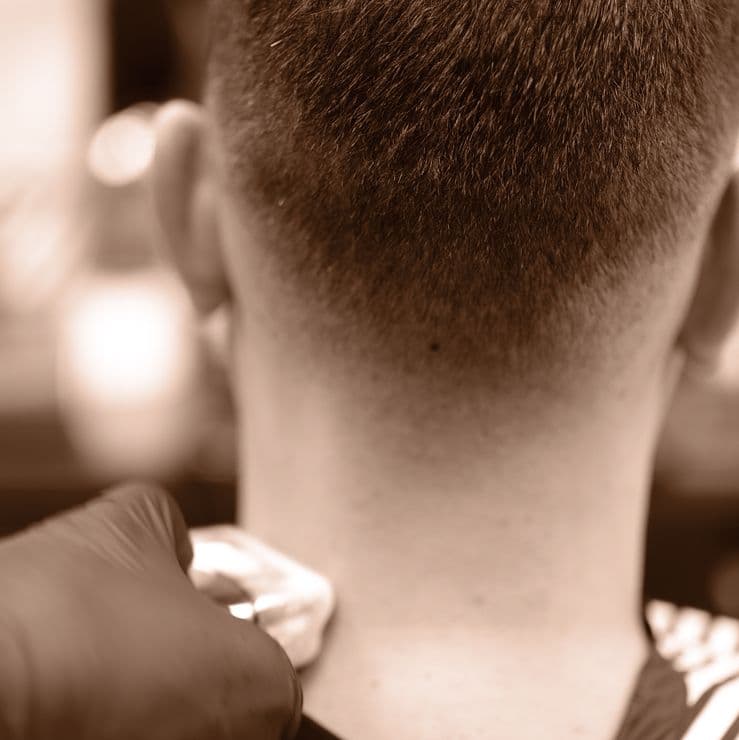 Barberare trimmar nacken på en kund med precision